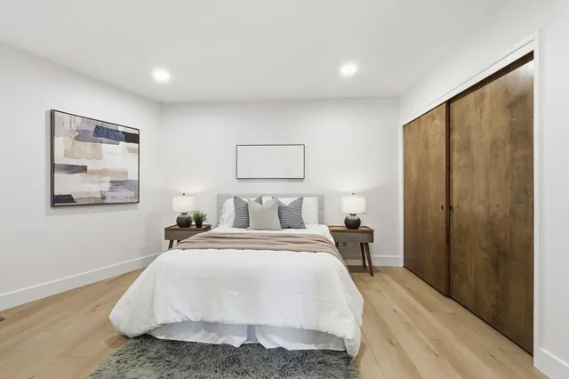 a spacious bedroom with a bed a table and large windows