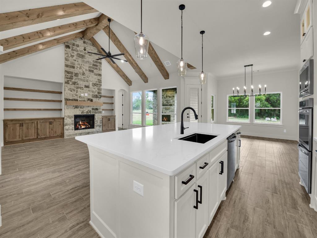 305 Wrangler Court Weatherford, TX 76088 - Photo 12 of 32 a large kitchen with kitchen island a stove a sink a center island and wooden floor