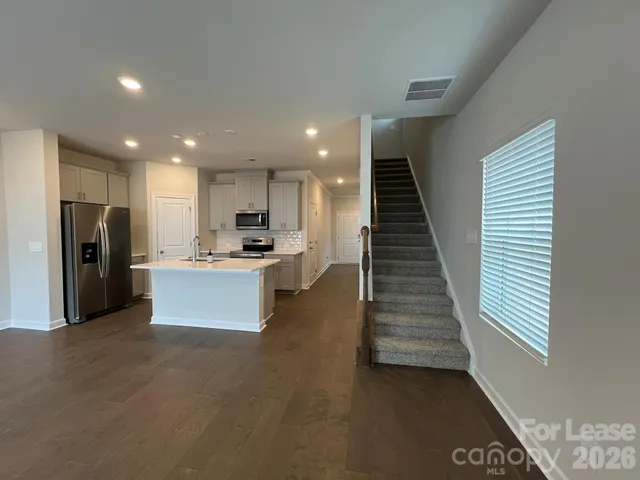 a large kitchen with stainless steel appliances kitchen island granite countertop a refrigerator and a stove