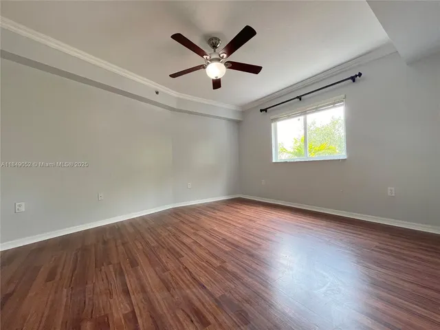 an empty room with wooden floor and ceiling fan