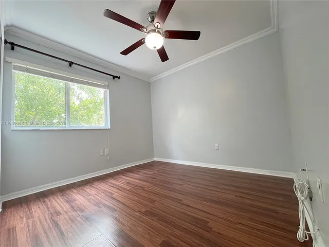 an empty room with wooden floor fan and windows