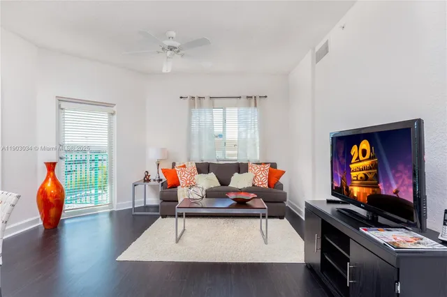 a living room with furniture a flat screen tv and a window
