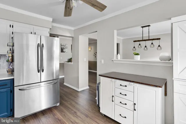 a kitchen with granite countertop a refrigerator and a wooden floor