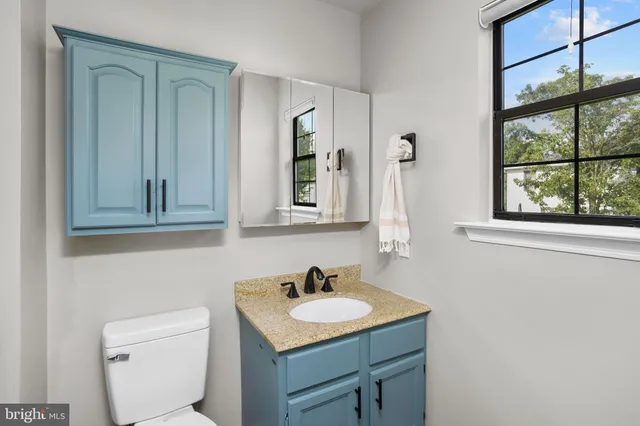 a bathroom with a granite countertop sink and a toilet