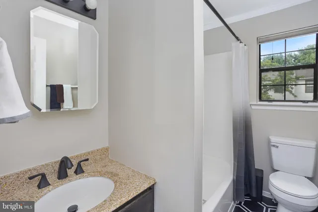 a bathroom with a granite countertop sink toilet and mirror