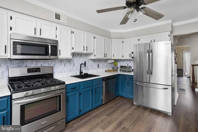 a kitchen with cabinets stainless steel appliances a sink and wooden floor