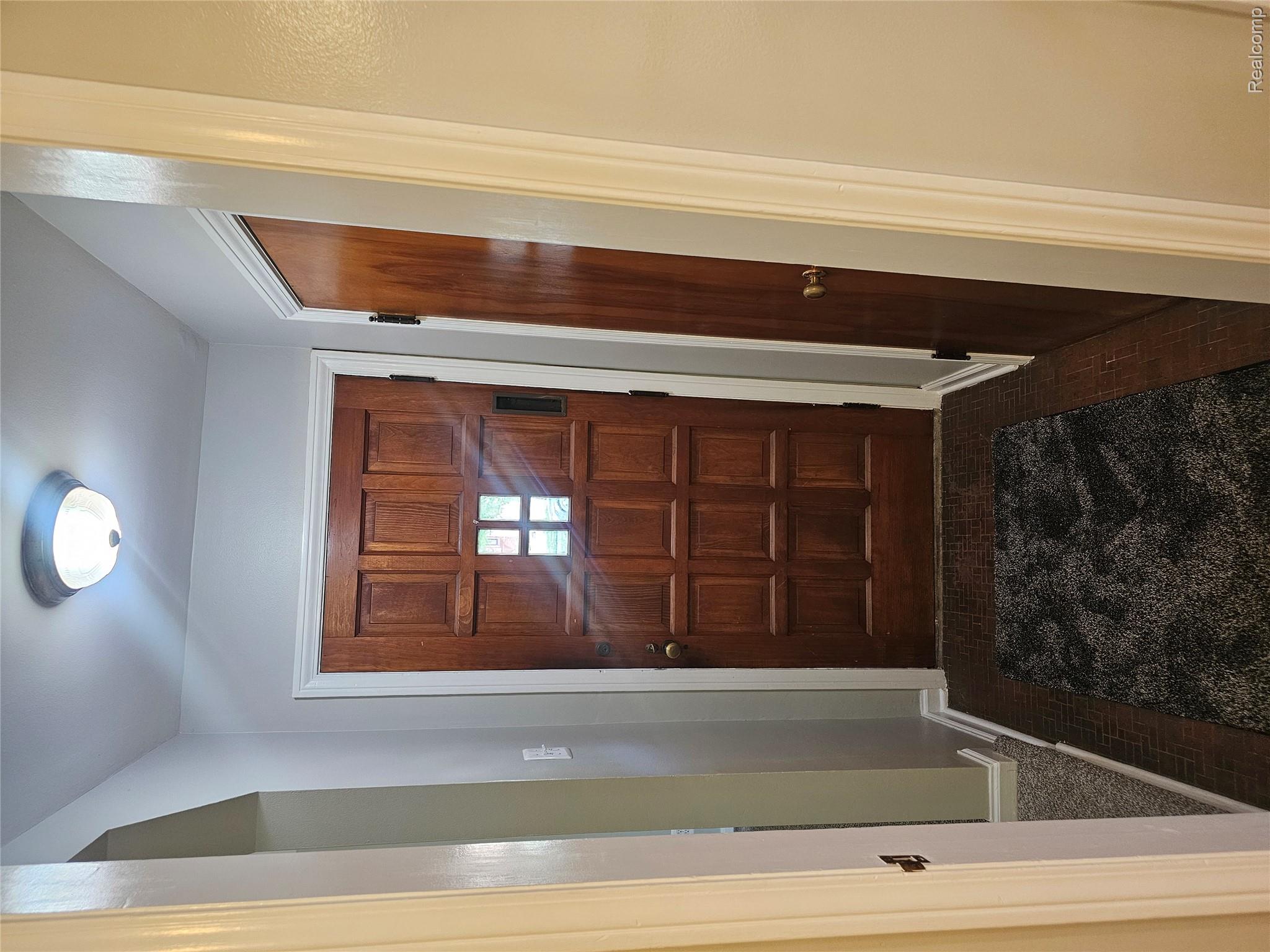 5240 Harvard Road Detroit, MI 48224 - Photo 4 of 18 Solid wood paneled entry door with clear glass window inserts, set against light gray walls with white trim, featuring a flush mount ceiling light fixture