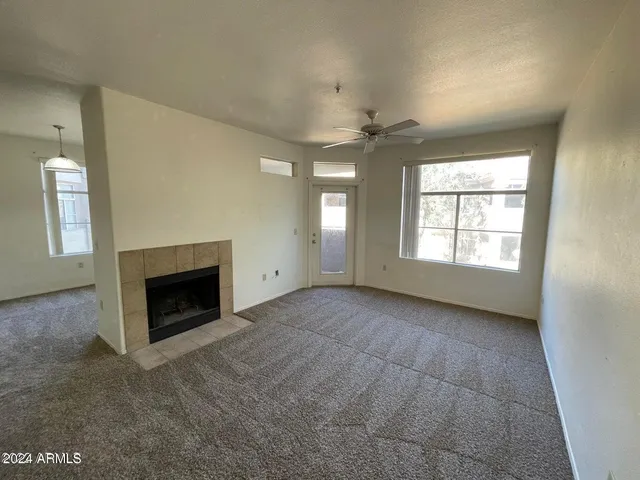 an empty room with windows and fireplace