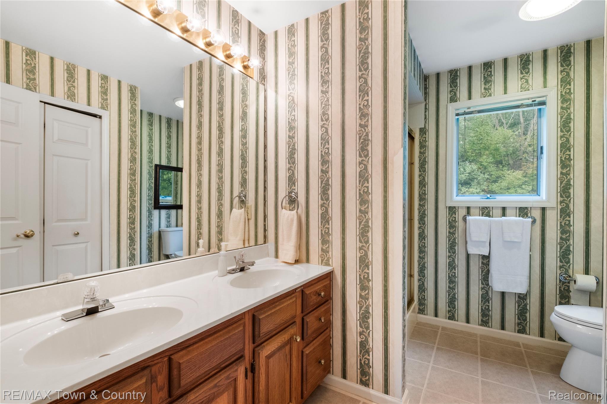 5464 North Seymour Road Flushing, MI 48433 - Photo 19 of 45 Dual vanity with integrated sinks, wood cabinetry, large mirror, and tiled flooring
