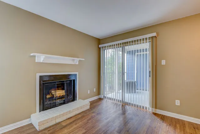 a view of an empty room with wooden floor fireplace and a window