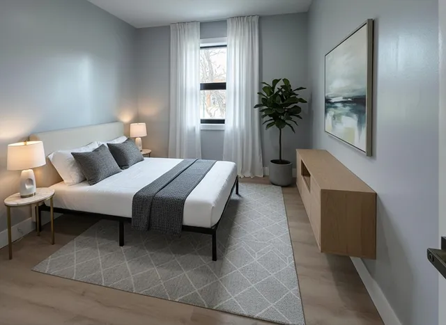 a bedroom with a bed table flowerpot and a window