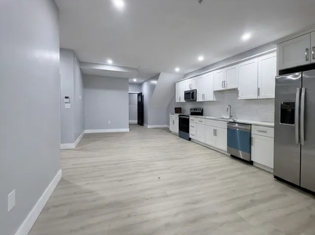 a large kitchen with stainless steel appliances kitchen island a large counter top and a stove top oven