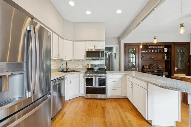 a kitchen with stainless steel appliances granite countertop a stove top oven a sink and a refrigerator