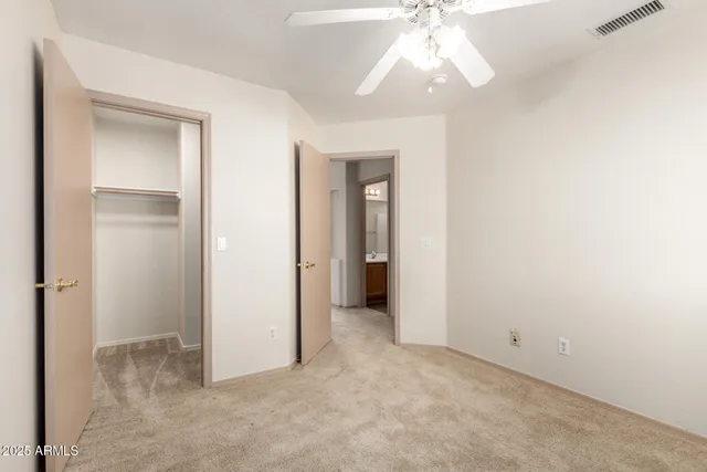 an empty room with a bathroom and a chandelier fan