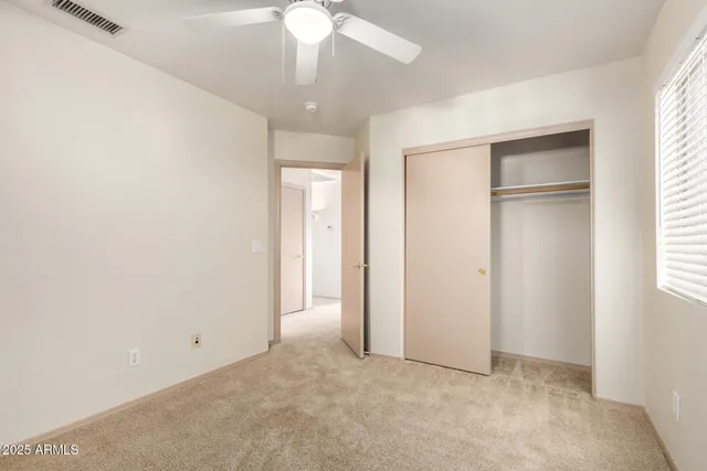 an empty room with a chandelier fan and windows