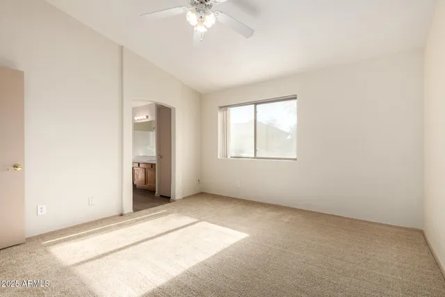 an empty room with chandelier fan and windows