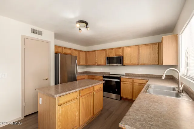 a kitchen with stainless steel appliances granite countertop a stove a sink dishwasher a refrigerator and a microwave oven with wooden floor