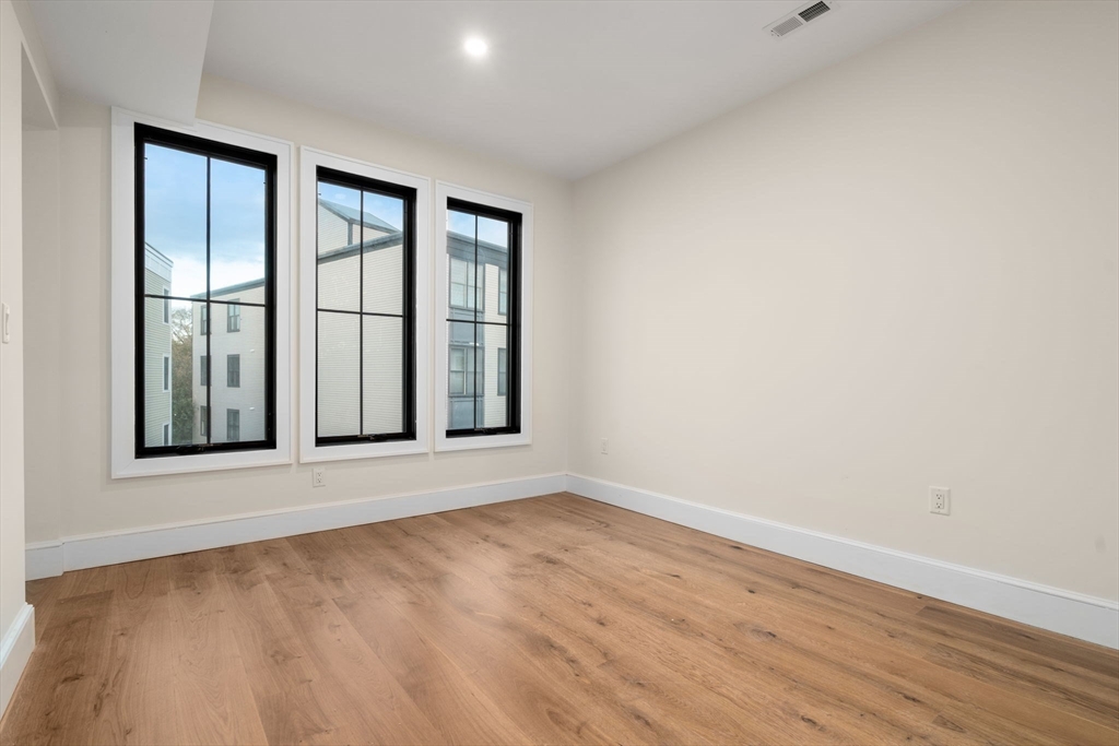34 Vinton Street, Unit 3 Boston, MA 02127 - Photo 14 of 29 an empty room with wooden floor and windows