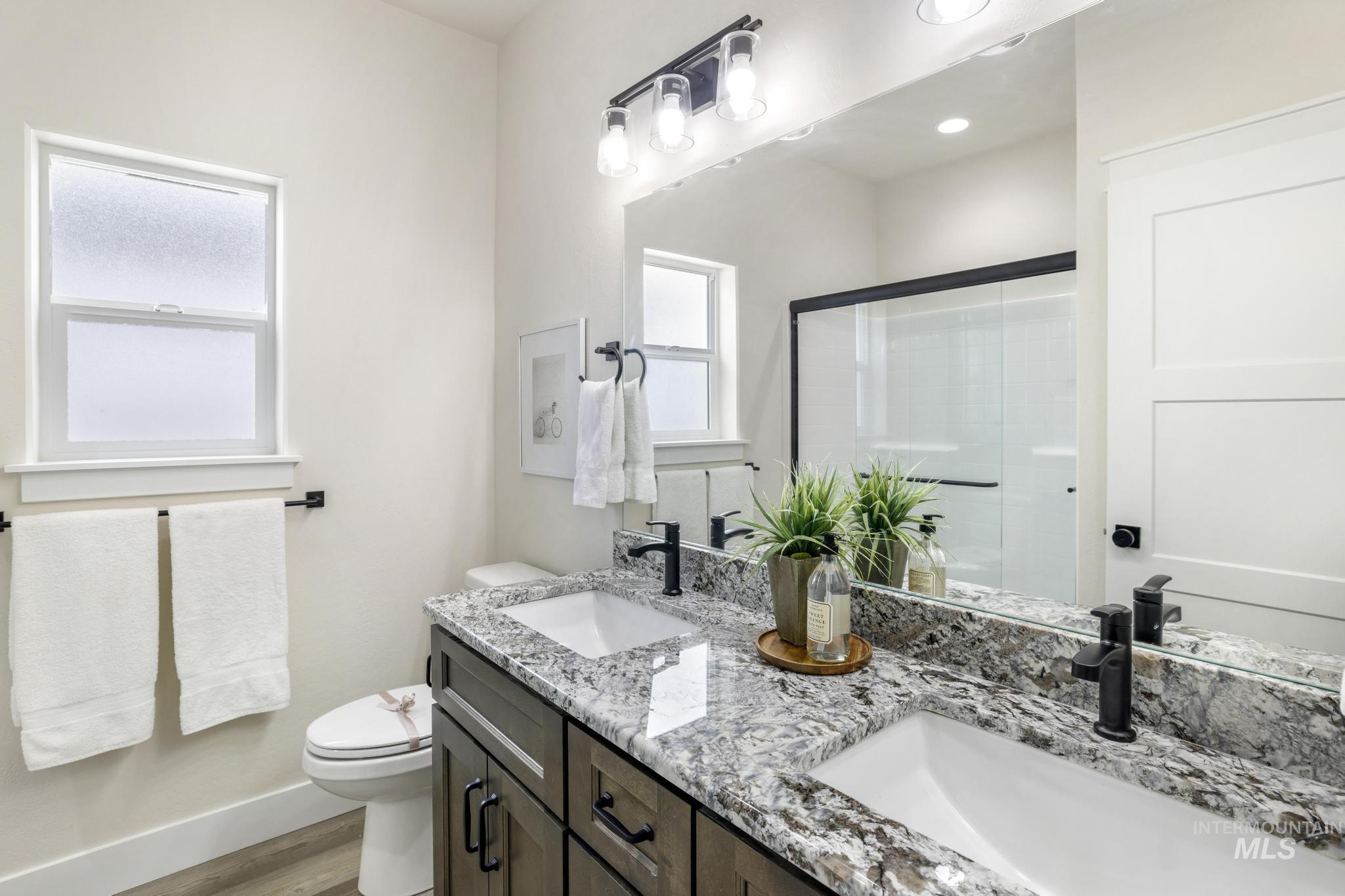 928 Gregory Way Twin Falls, ID 83301 - Photo 15 of 24 Full bathroom with a shower stall, double vanity, and light wood-style flooring