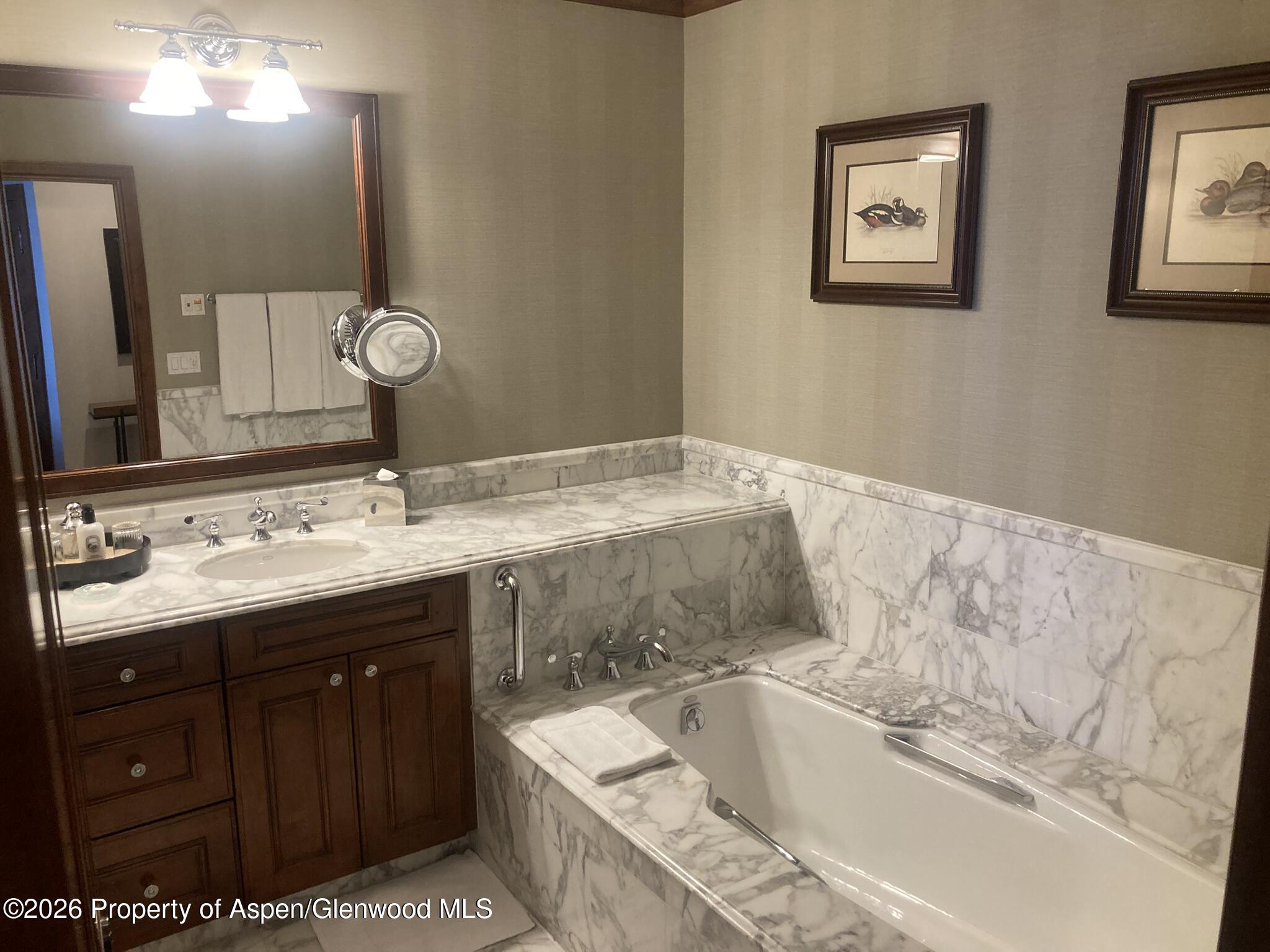 39 Boomerang Road, Unit 841010 Aspen, CO 81611 - Photo 12 of 21 a bathroom with a granite countertop bathtub sink vanity and mirror