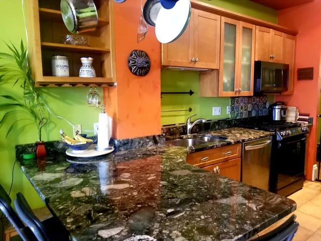 a kitchen with stainless steel appliances granite countertop a sink a stove and a wooden cabinets