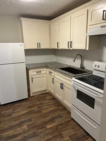 a kitchen with granite countertop white cabinets and white appliances
