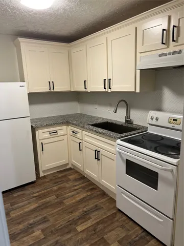 a white kitchen with granite countertop white cabinets and white appliances