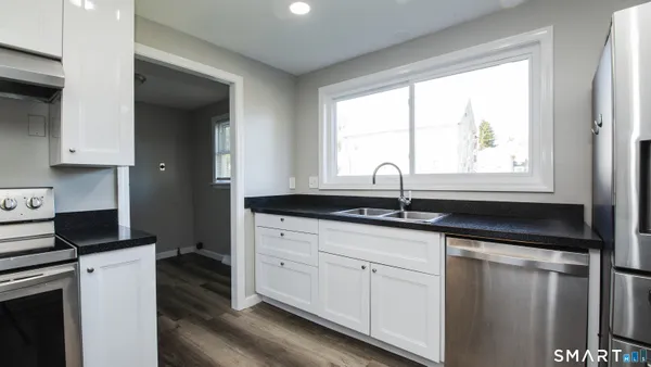 a kitchen with granite countertop white cabinets and a window