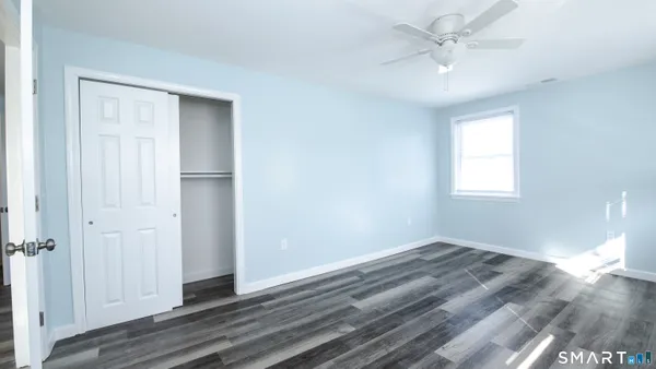a view of empty room with wooden floor and fan