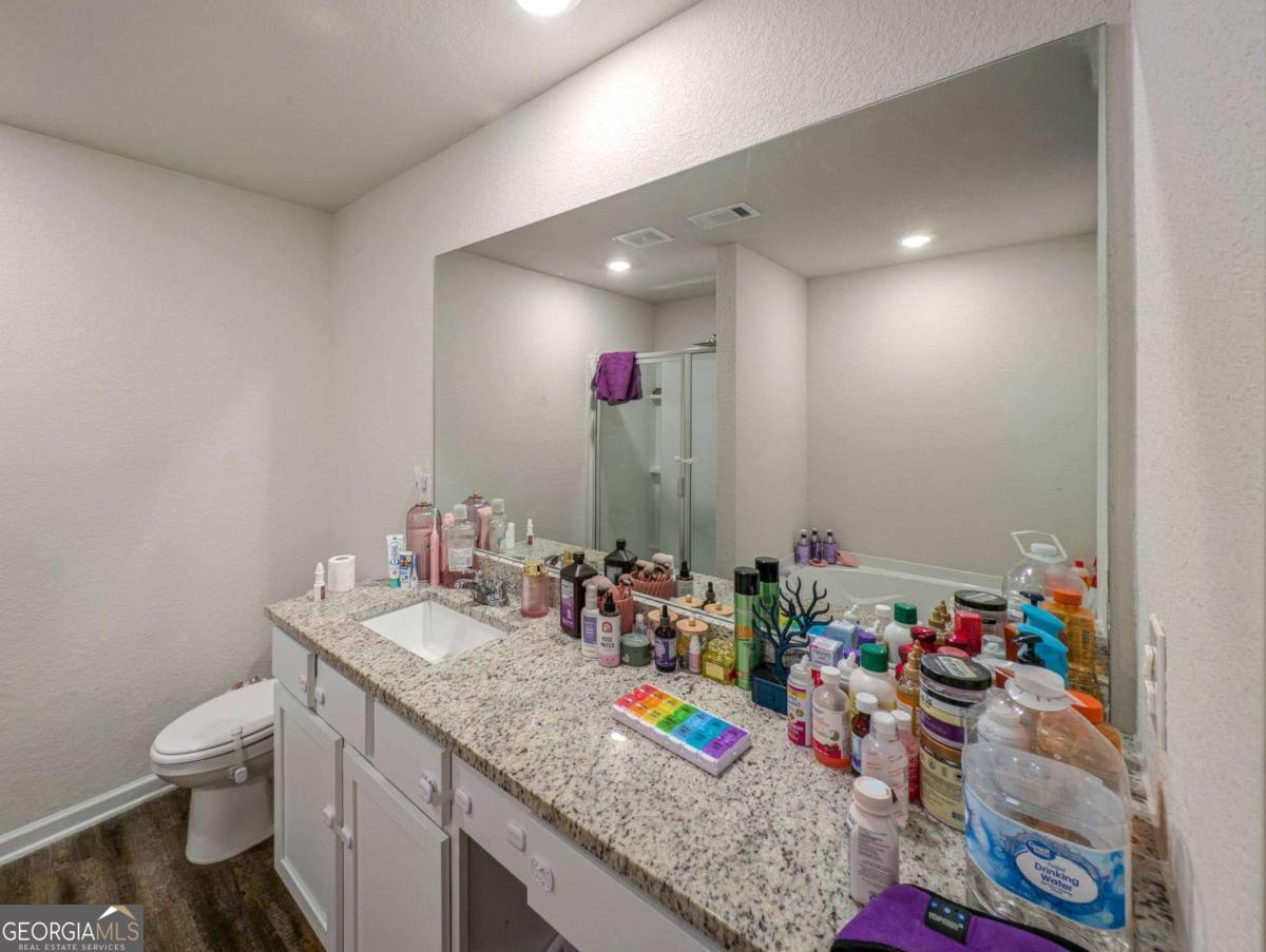 653 Meadows Farm Way Monroe, GA 30655 - Photo 22 of 34 a bathroom with a granite countertop sink a large mirror and shower