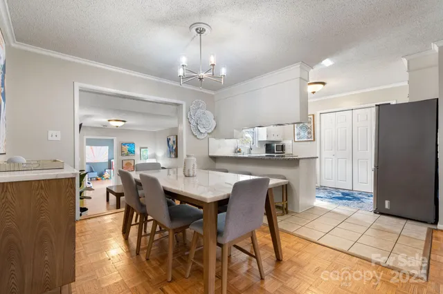 a kitchen with stainless steel appliances kitchen island granite countertop a dining table chairs and a refrigerator