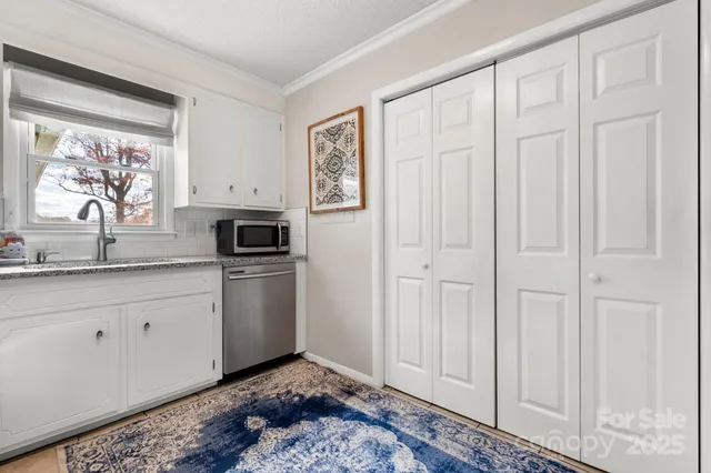 a kitchen with white cabinets and sink