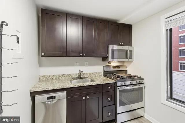 a kitchen with granite countertop stainless steel appliances a stove microwave and sink