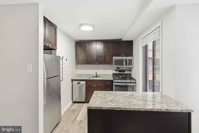 a kitchen with granite countertop kitchen island stainless steel appliances a refrigerator stove top oven and sink