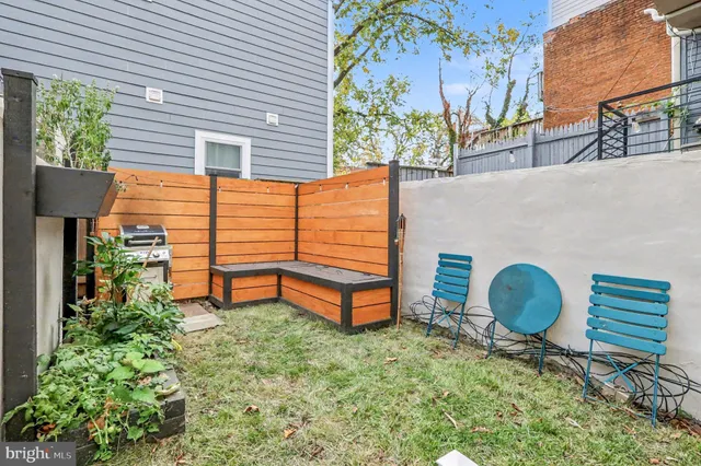 a backyard of a house with wooden fence and a large tree
