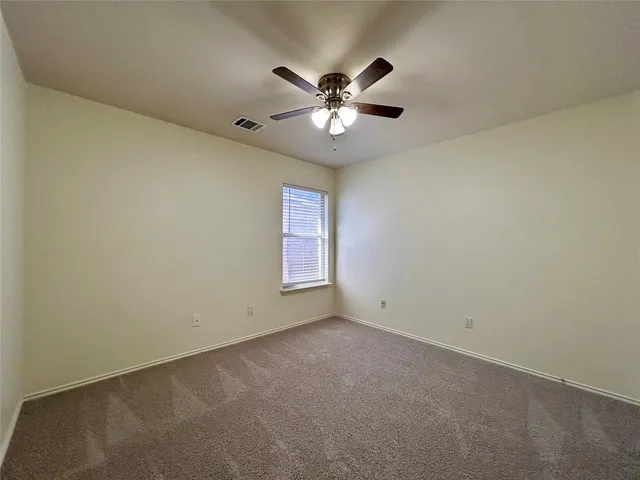 an empty room with a window and a fan