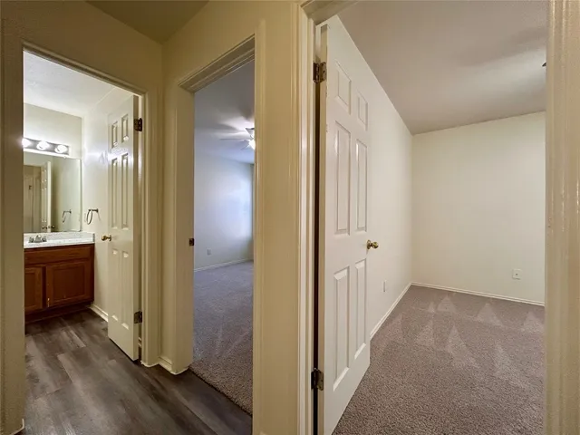 a view of a hallway with bathroom and wooden floor