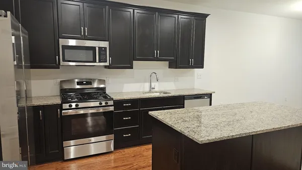 a kitchen with stainless steel appliances kitchen island granite countertop a stove a sink and a microwave