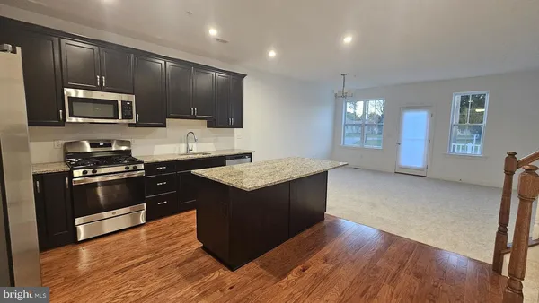 a kitchen with stainless steel appliances granite countertop sink stove refrigerator and cabinets
