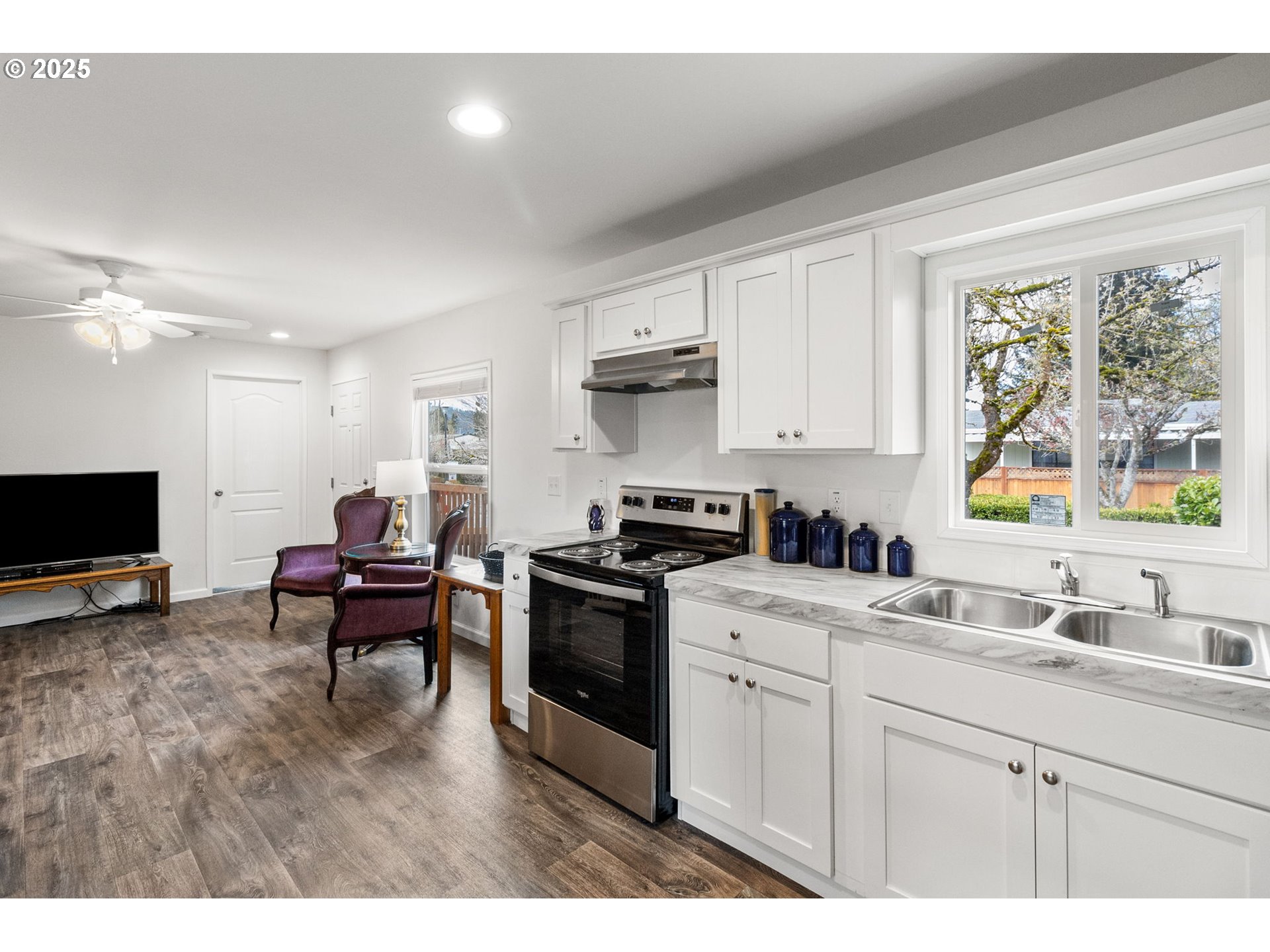 5335 Main Street, Unit 187 Springfield, OR 97478 - Photo 15 of 39 a kitchen with stainless steel appliances granite countertop a stove top oven a sink dishwasher and white cabinets with wooden floor