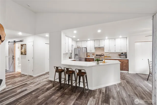 a kitchen with stainless steel appliances a dining table chairs refrigerator sink and cabinets