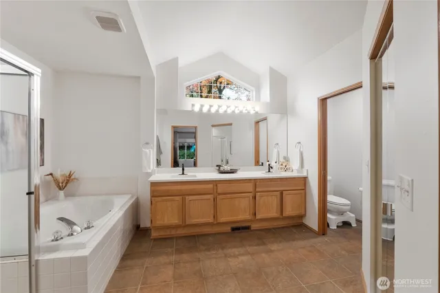 a spacious bathroom with a tub sink and mirror