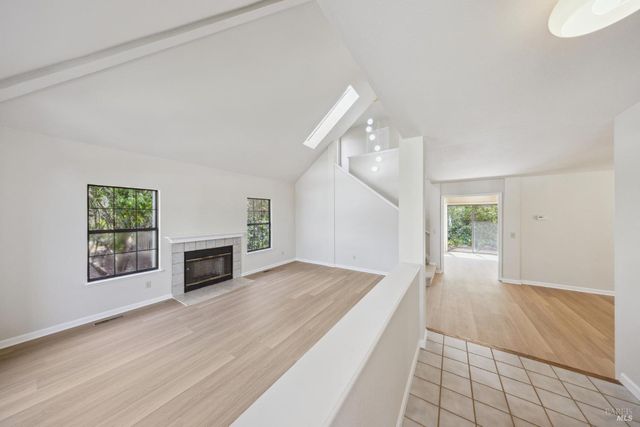 an empty room with wooden floor fireplace and windows