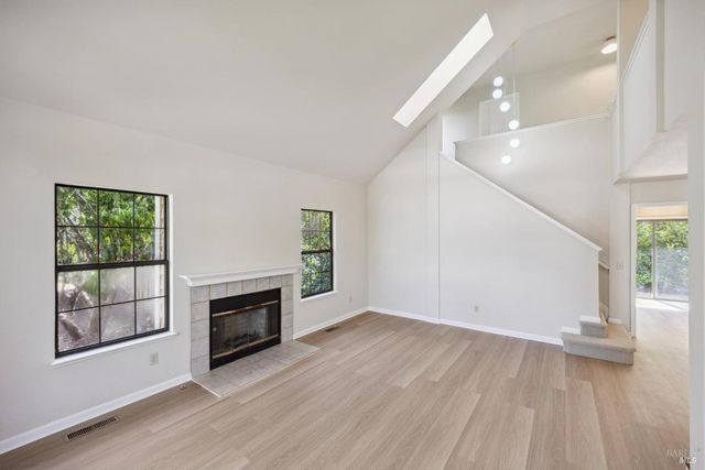a view of an empty room with wooden floor and a kitchen