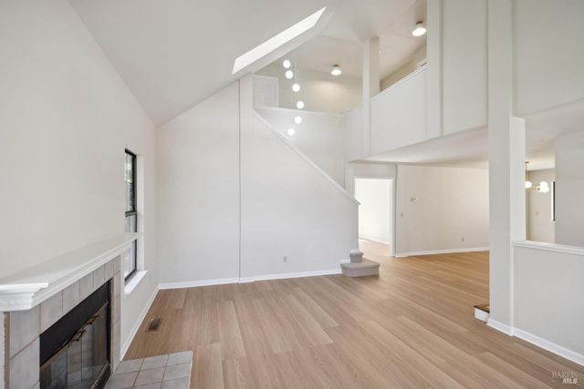 an empty room with wooden floor cabinet and windows