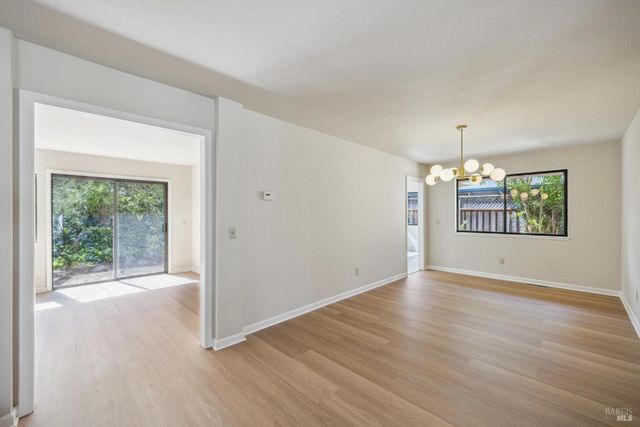 an empty room with wooden floor and chandelier