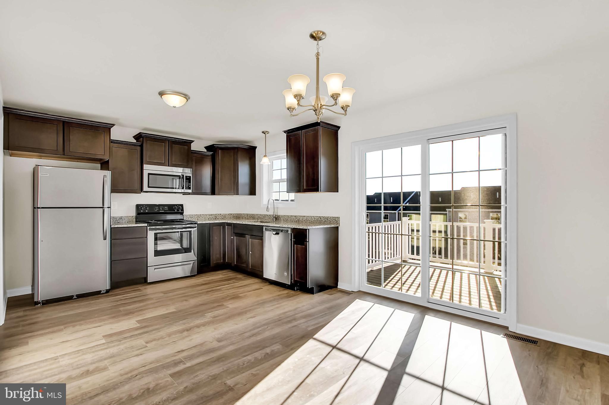 51 Overlook Dr., Unit I Hanover, PA 17331 - Photo 3 of 14 a kitchen with stainless steel appliances a stove top oven a sink dishwasher a refrigerator and a dining table with wooden floor
