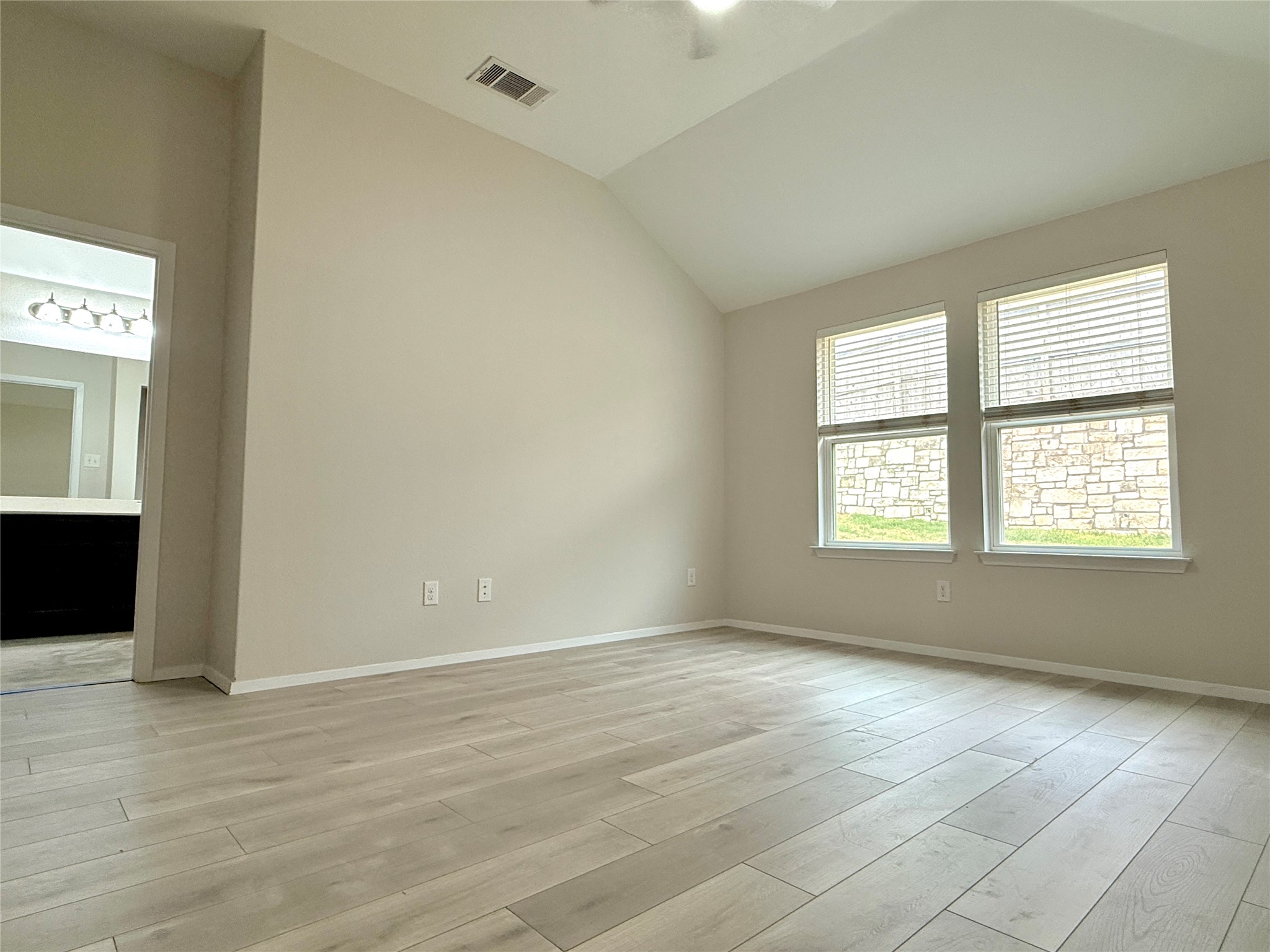 5629 Corso Court Austin, TX 78747 - Photo 13 of 23 Unfurnished room featuring vaulted ceiling, light wood-style floors, and ceiling fan