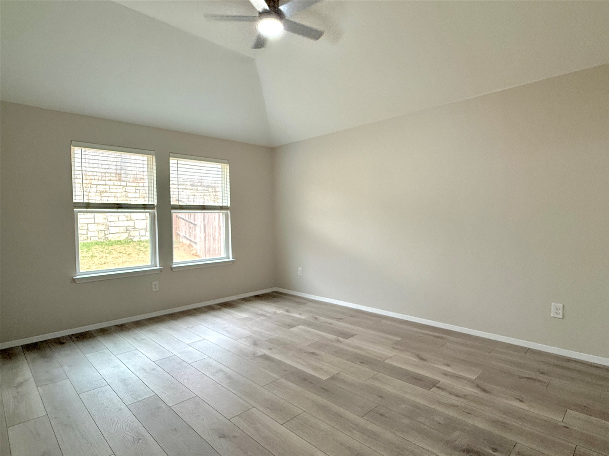 5629 Corso Court Austin, TX 78747 - Photo 14 of 23 Empty room with ceiling fan, light wood-type flooring, and lofted ceiling