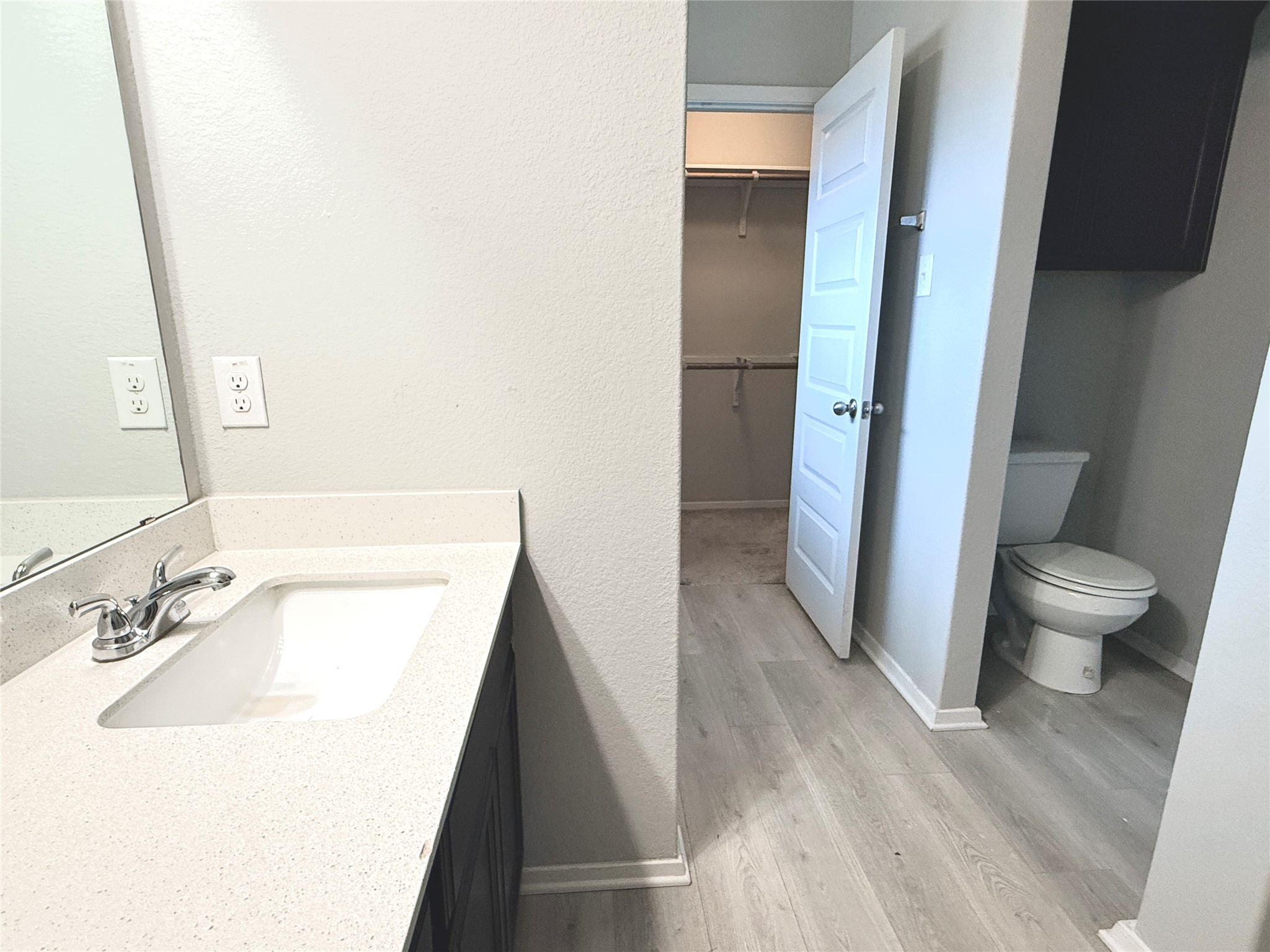 5629 Corso Court Austin, TX 78747 - Photo 18 of 23 Bathroom with vanity, a spacious closet, light wood-style floors, and a textured wall